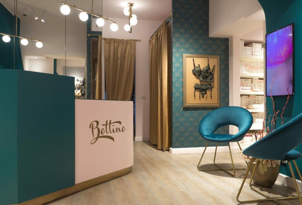 Restyling di un negozio di intimo con colori raffinati come verde petrolio e rosa pallido, in un’atmosfera elegante ispirata allo stile art-decò anni '30
